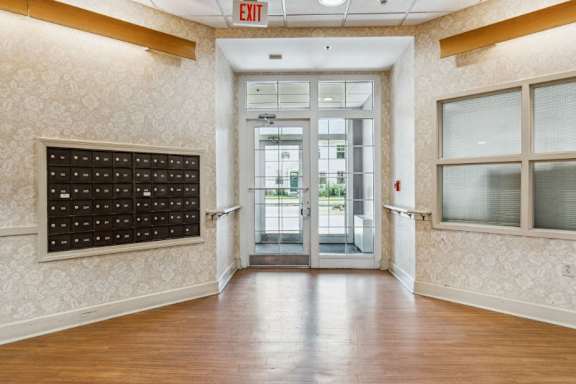 A hallway with a black mailbox and a red exit sign above the door at Monterey Place, New Haven, 06511