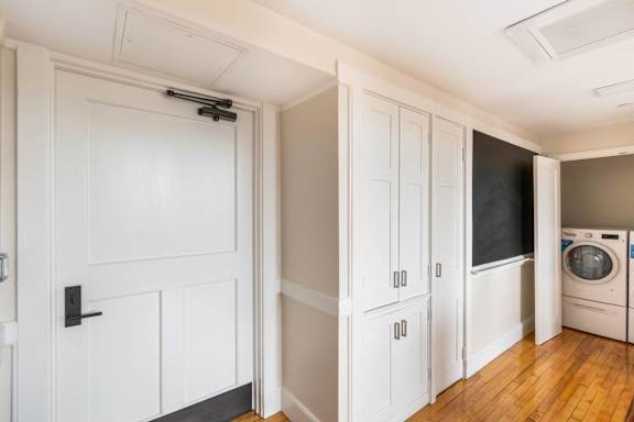 a laundry room with white cabinets and a washing machine at Beverly Village for Living & the Arts Apartments, Beverly, 01915