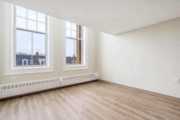 an empty room with wood floors and large windows at Chapman House, E. Boston