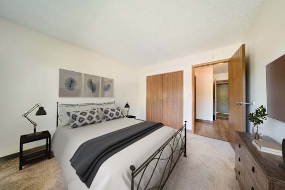 A bedroom with a bed, nightstand, and a painting on the wall.