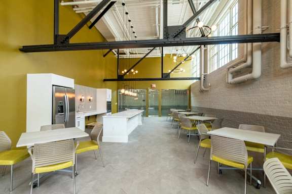 a dining room with tables and chairs and a kitchen at Beverly Village for Living & the Arts Apartments, Beverly, 01915