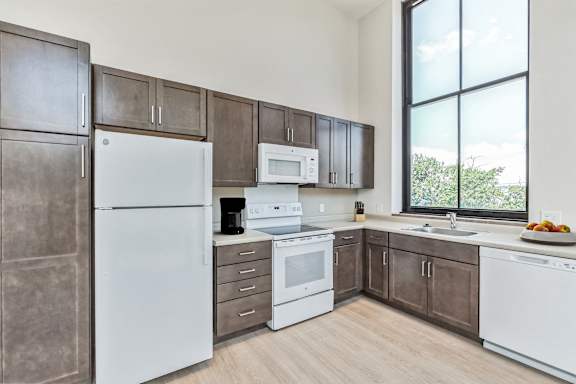 a kitchen with white appliances and brown cabinets and a window