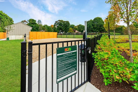 a gate with a sign on it in front of a garden at Beverly Village for Living & the Arts Apartments, Beverly, 01915
