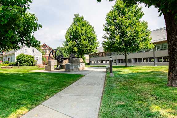 a sidewalk in front of a building with trees and a statue at Ames Shovel Works Apartments, Massachusetts, 02356