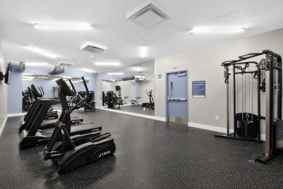 A gym with a variety of equipment including treadmills, weights, and exercise machines.