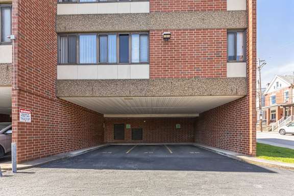 A parking garage with a brick wall and a white car parked in front.