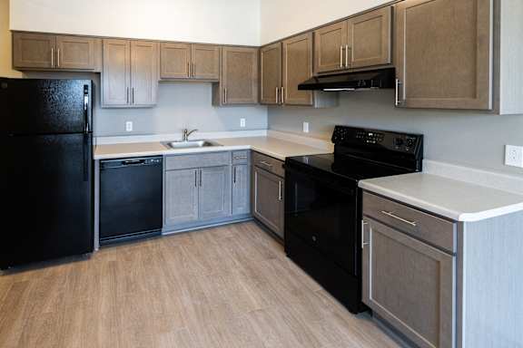 A kitchen with black appliances and wooden cabinets at 35 Broadway, Menands, NY.