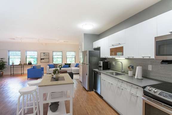 a kitchen and living room with white cabinets and a table and chairs at Ames Shovel Works Apartments, Massachusetts, 02356