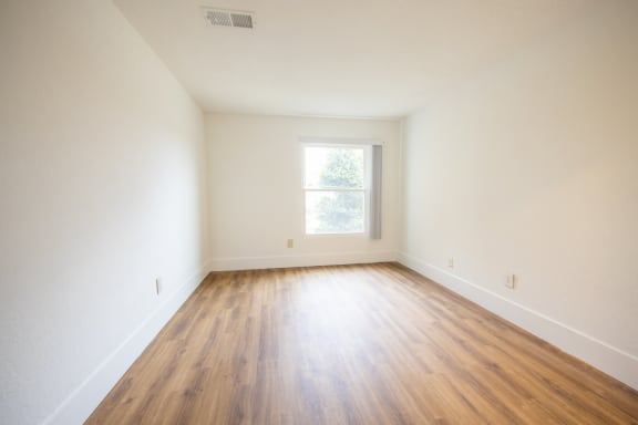 an empty room with hardwood floors and a window