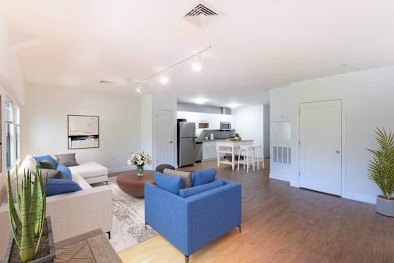 a living room with couches and a table with a kitchen in the background at Ames Shovel Works Apartments, Massachusetts, 02356