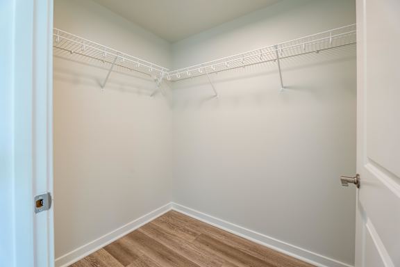 A white closet with a door and a shelf.