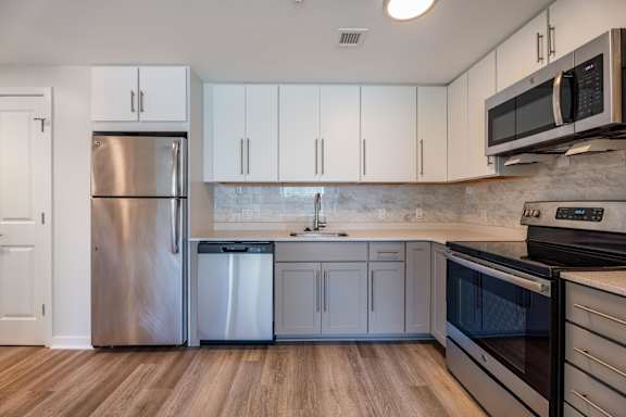 a kitchen with white cabinets and stainless steel appliances at North Square Apartments at The Mill District, Massachusetts