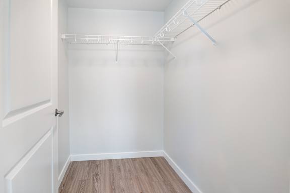 A white closet with a white door and a white shelf.