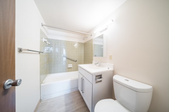 A white toilet sits next to a white sink in a small bathroom at Highpoint Towers Apartments, Erie, PA