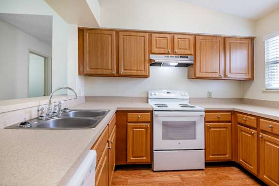 A kitchen with wooden cabinets and a white stove top oven at Fisherman's Landing Apartments, Ormond Beach, Florida