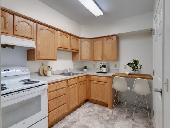 a kitchen with white appliances and wooden cabinets at Chambers Senior Housing Apartments, Kingston, NY