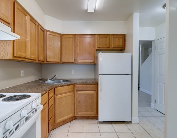 a kitchen with a white refrigerator freezer next to a stove top oven at Birchwood Village Apartments, Kingston, New York