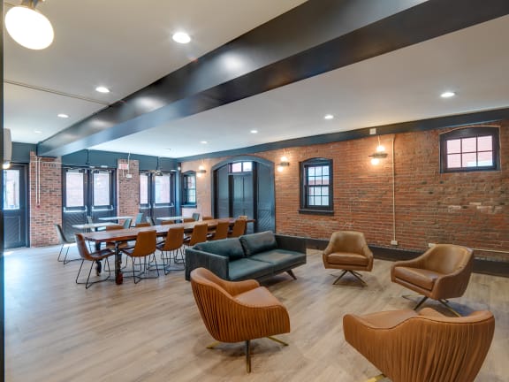 a lounge area with chairs and tables and a brick wall at Ninth Square Apartments, New Haven, CT