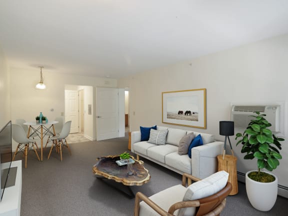 A living room with a white couch, a coffee table, and a painting on the wall at Chambers Senior Housing Apartments, Kingston, NY