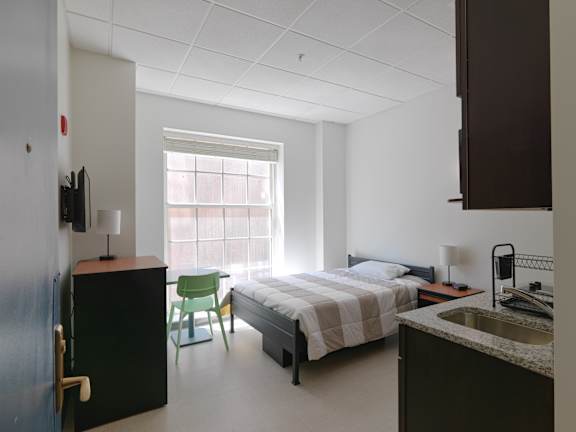 a bedroom with a bed and a sink and a chair at 140 Clarendon, Boston, MA