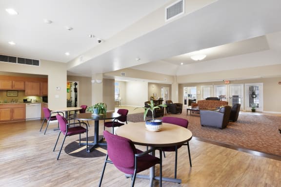 a resident clubhouse with tables chairs and a kitchen in the background at Creekwood Apartments, Watertown, 13601