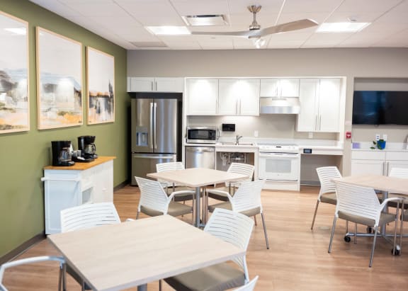A kitchen with white chairs and a table at Highpoint Towers Apartments, Erie, PA