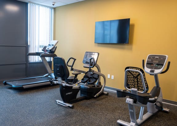 A gym with a treadmill, elliptical trainer and a stationary bike at Highpoint Towers Apartments, Erie, PA