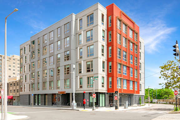 A modern multi-story building with a red and grey facade at Pok Oi Residences, Boston, MA, Massachusetts, 2111