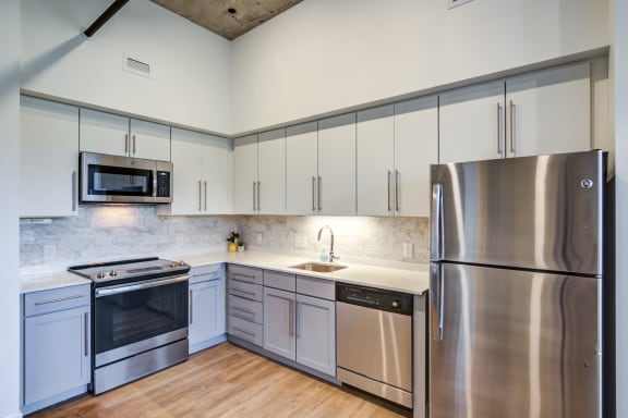 an empty kitchen with stainless steel appliances and white cabinetsat Montgomery Mill in Windsor Locks, CT