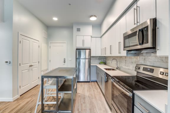 a kitchen with white cabinets and stainless steel appliances at North Square Apartments at The Mill District, Massachusetts