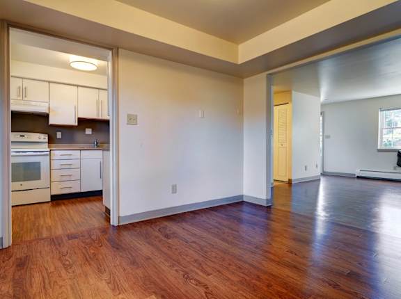A kitchen with white cabinets and a wooden floor at Colonial Estates Apartments, Massachusetts, 01119
