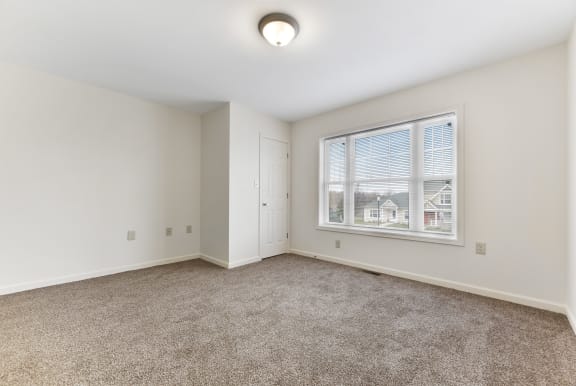 a bedroom with a large window and carpet  at Summit Wood Apartments, Watertown, 13601