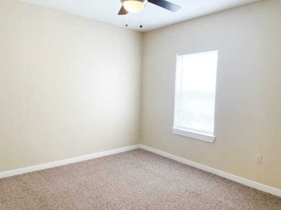an empty room with a ceiling fan and a window