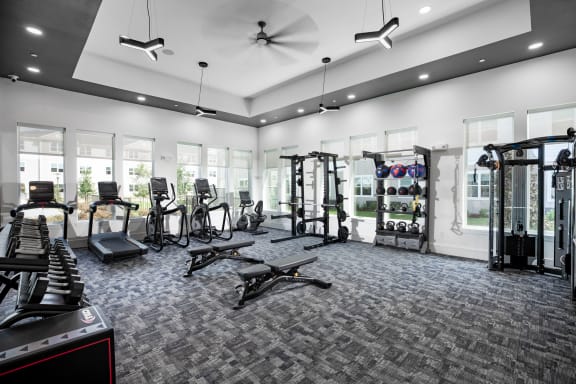 a spacious fitness room with cardio equipment and windows at 55 Fifty at Northwest Crossing, Texas, 77092