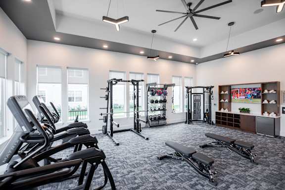 A gym with treadmills, weights, and exercise benches at 55 Fifty at Northwest Crossing, Houston, TX 77092