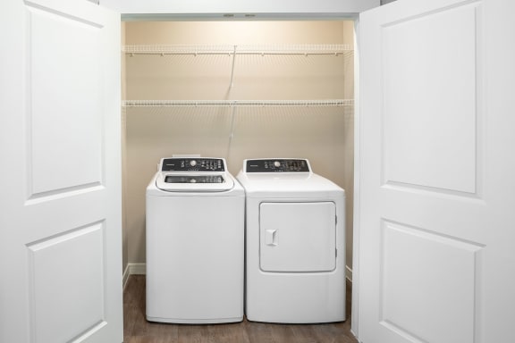 a washer and dryer in a laundry room with white doors at 55 Fifty at Northwest Crossing, Houston