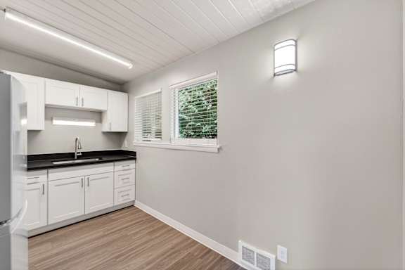A kitchen with white cabinets and a black countertop.