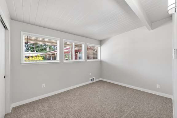 A room with a carpeted floor and a window with blinds.