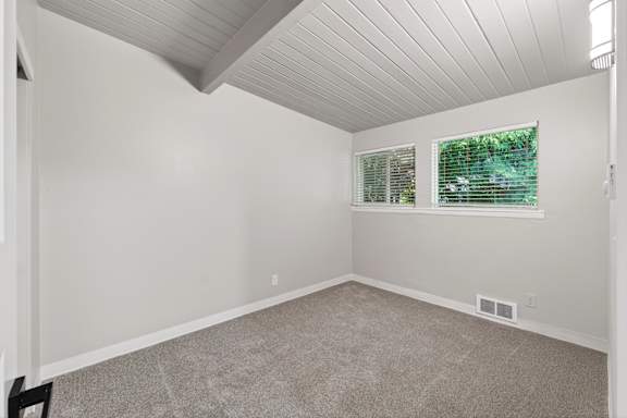 A room with a window and a carpeted floor.