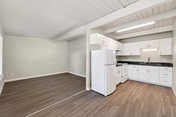 A kitchen with white cabinets and a white refrigerator.