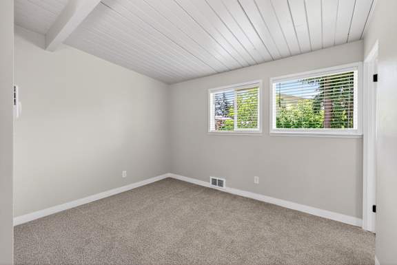 A room with a carpeted floor and a window with blinds.