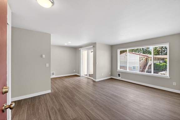 A room with a wooden floor and a door leading to a balcony.