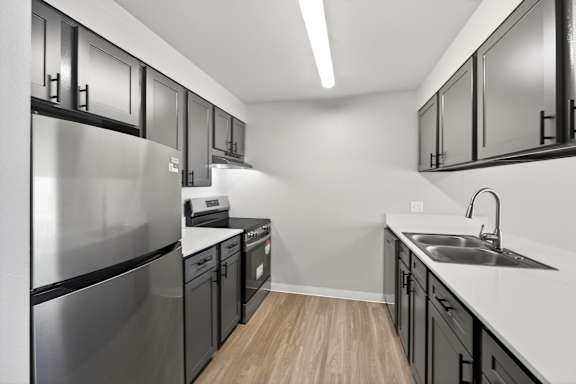 A modern kitchen with stainless steel appliances and black cabinets.