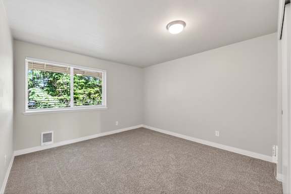 A room with a window and a carpeted floor.