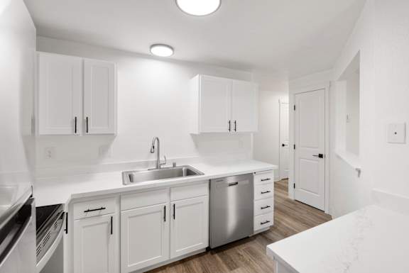 A kitchen with white cabinets and a marble countertop.