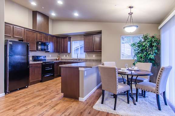A kitchen with a table and chairs in front of a window.