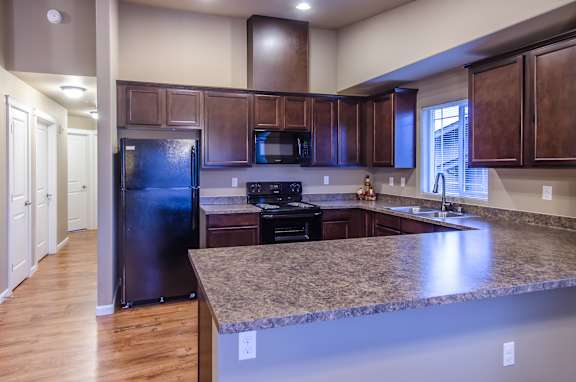 A kitchen with a granite countertop and dark brown cabinets.