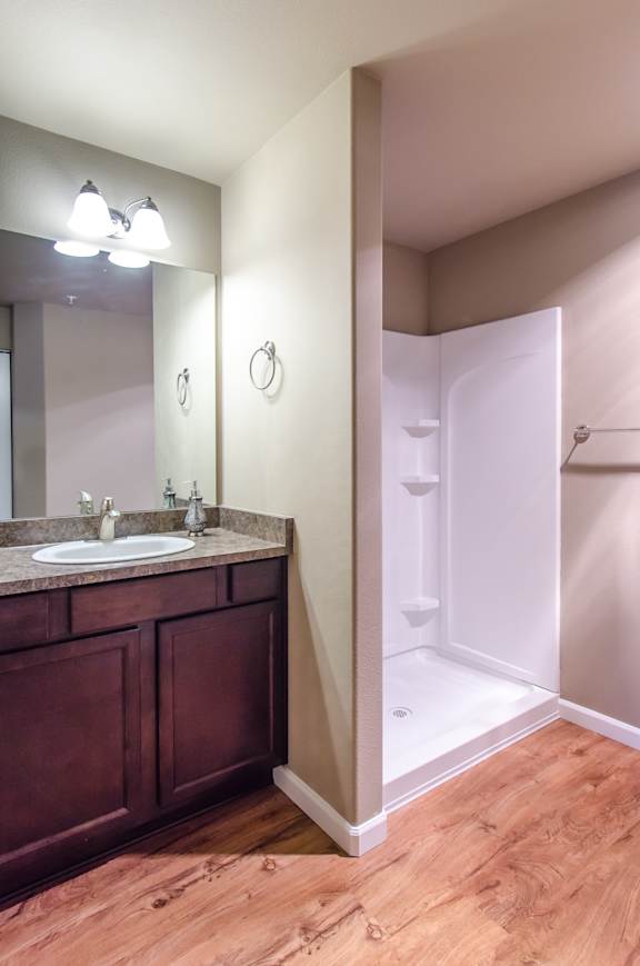 A bathroom with a sink, mirror, and shower.