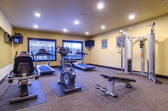 A well-equipped gym with various exercise machines and a bench.