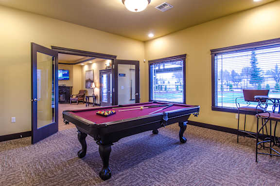 A pool table is in the middle of a room with a door and a window.